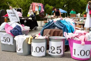 Containers labeled with prices holding merchandise being sold at a garage sale