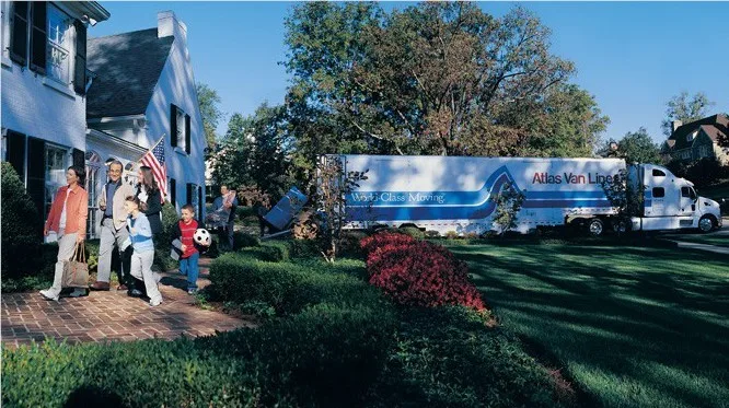 Family walking into a house with a moving truck in the driveway