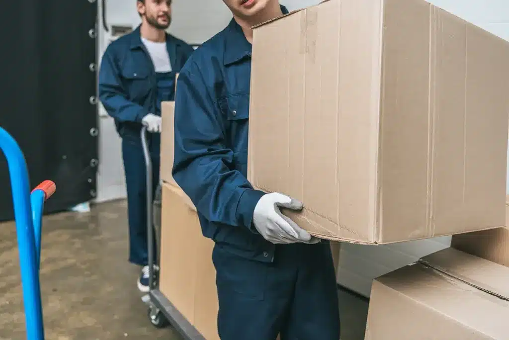 two movers in uniform transporting boxes